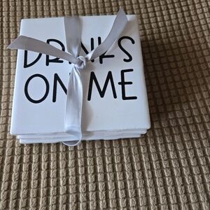 NWOT White Stone Coasters with Black Text DRINKS ON ME. Cork Back